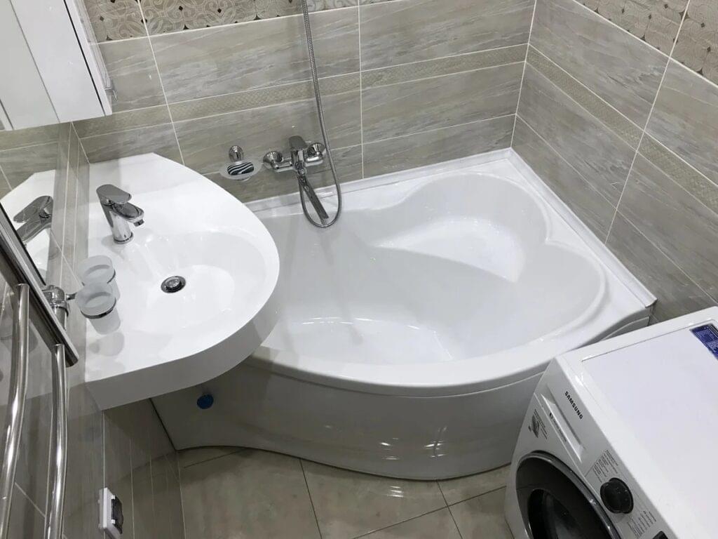 Белые ванна и мойка. На заднем плане плитка серого цвета